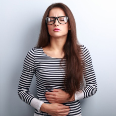 Photograph of a woman clutching her stomach in pain